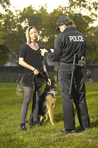 警察在制服检查夫人与德国牧羊人在城市公园 — 图库照片