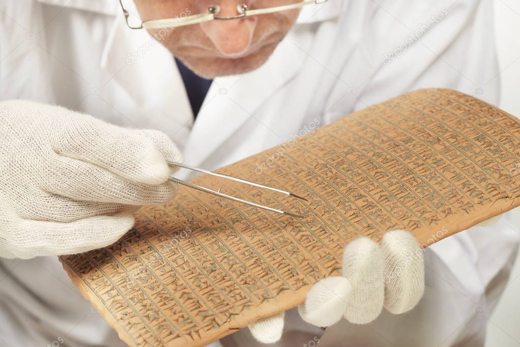 Scientist exploring ancient type of Akkad empire style cuneiform with tweezers