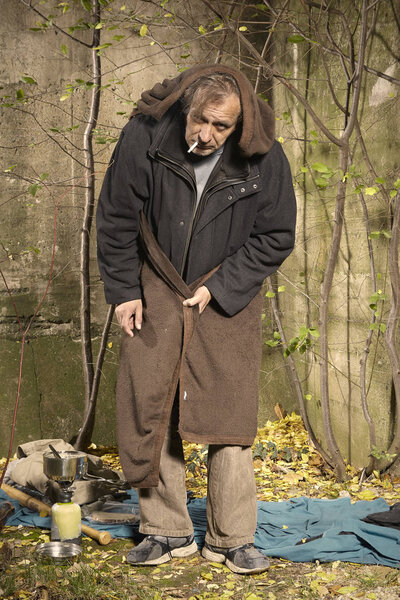 Уродливый нищий человек, живущий под открытым небом спит, расслабляется и лежит в одиночестве на скрытом городском месте
