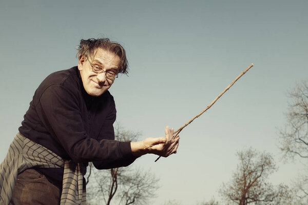 Man in ugly style dress practicing in dowsing with rods