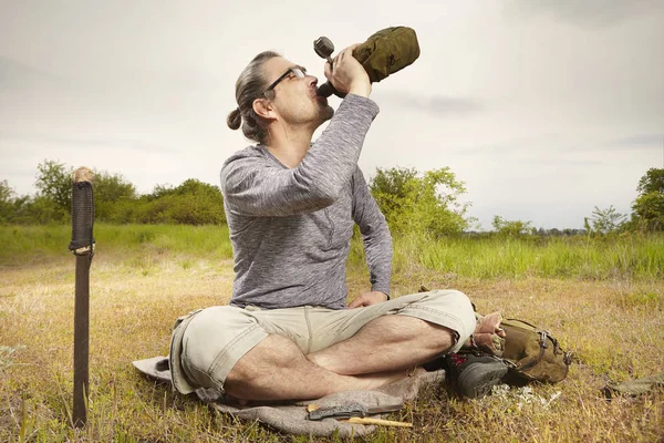 Mature man on trip in summer wilderness relaxing on meadow