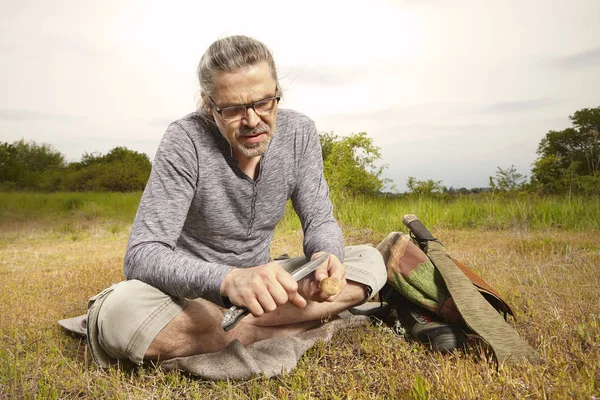 Mature man on trip in summer wilderness relaxing on meadow