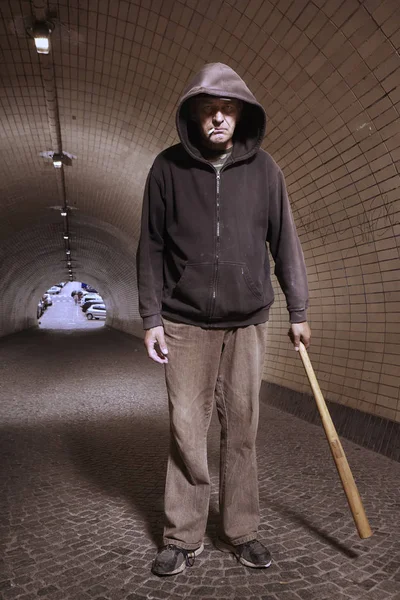 Older addict man in black hooded shirt with weapon