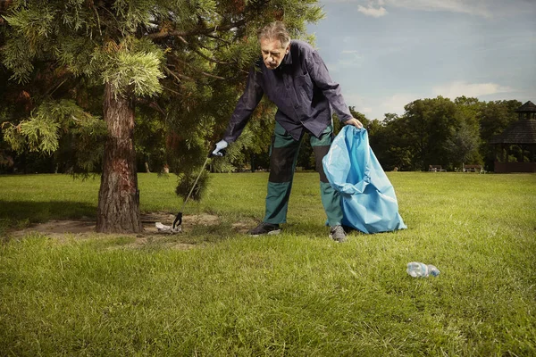 Man in public service cleaning up trash in city park