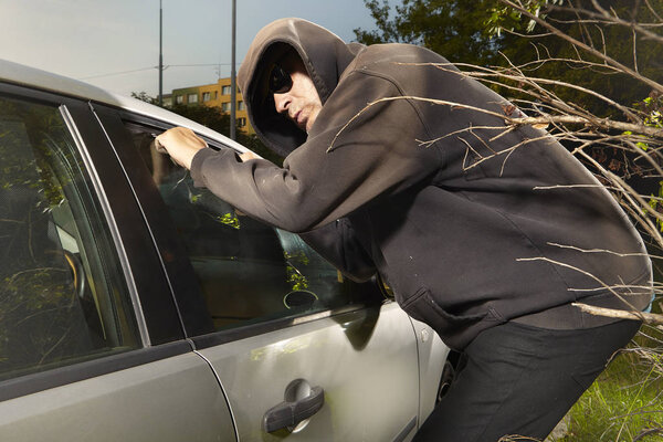 Addicted man in black hooded shirt entering and stealing car
