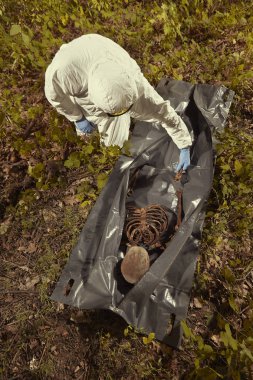 Gözlem için polis teknisyeni tarafından plastik ceset torbasına insan kalıntıları toplama