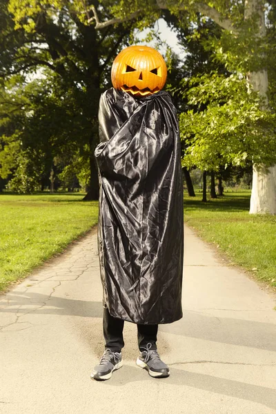 Older man in hooded cloak haunts in city park