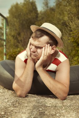 Eski tarz mayo ve hasır şapkalı komik adam iç boruyla poz veriyor.