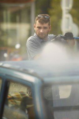 Oto yıkamadaki adam eski güzel arabasıyla ilgilenir.