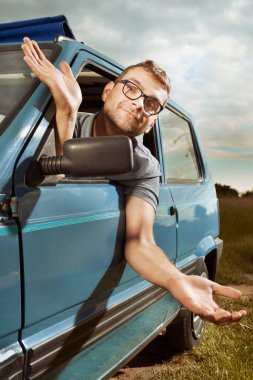 Küçük, sevimli eski arabasıyla yaz gezisine çıkan bir adam.