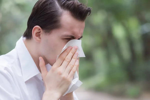 Man uses tissue paper sneezing due to having pollen allergy