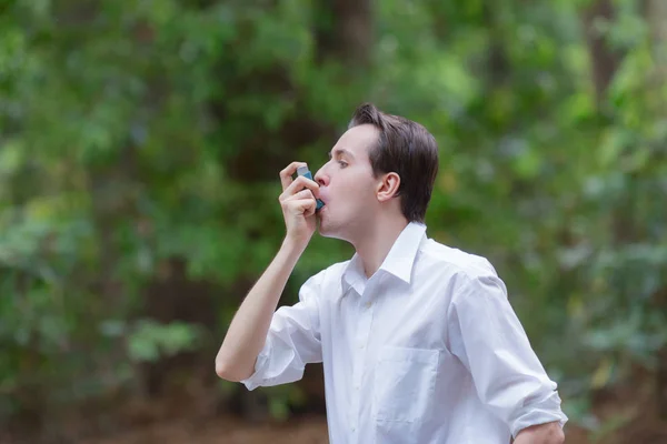 Hombre joven está usando un inhalador de asma — Foto de Stock