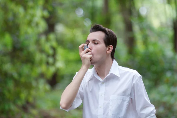 Hombre joven está usando un inhalador de asma — Foto de Stock