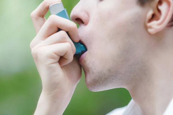 Hombre joven está usando un inhalador de asma — Foto de Stock