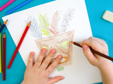 Bir çocuk bir Hint maskesi çizer.