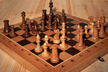 Tahta bir masanın üzerinde taşlarla satranç tahtası.