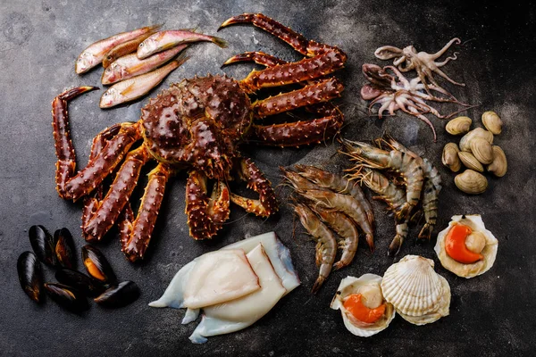 Raw Seafood - King Crab, Prawn Shrimp, Clams, Scallops, Octopus, Squid, Mullet fish on dark background