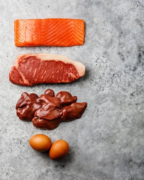 Raw food selection for Ketogenic diet Egg, Chicken Liver, Beef meat Steak and Salmon fish Steak on gray concrete background copy space — Stock Image Raw Food Selection Ketogenic Diet Egg Chicken Liver Beef Meat Stock Image