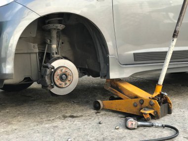 Jack Hidrolik tekerleksiz araba kaldırıyor ve yeni lastik değişimi için bekliyor.