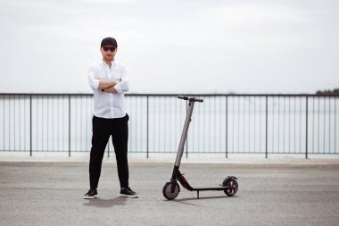 Beyaz gömlek ve siyah pantolon Street elektrikli scooter ile ayakta modern insan kılığında