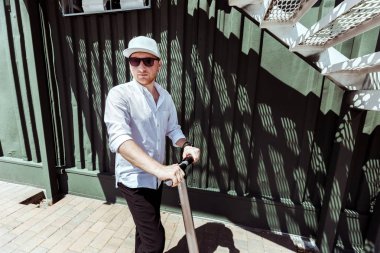Beyaz gömlek ve siyah pantolon Street elektrikli scooter ile ayakta modern insan kılığında
