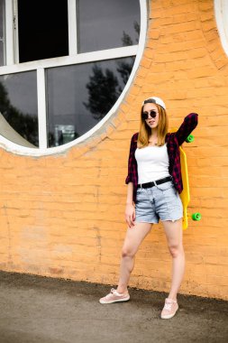 Neşeli kız portakal duvara sarı kaykay ile poz