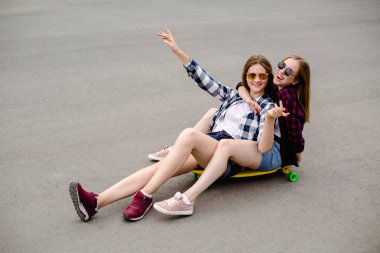 Arkadaşlar eğlenmeye gülümseyen iki sarı longboard sokaklarda sürme. Dostluk kavramı