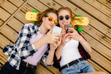 Hipster kıyafeti ile yalan ahşap iskele üzerinde selfie yapma iki genç kız