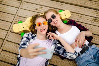 Hipster kıyafeti ile yalan ahşap iskele üzerinde selfie yapma iki genç kız