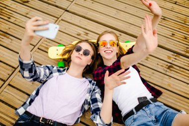Hipster kıyafeti ile yalan ahşap iskele üzerinde selfie yapma iki genç kız