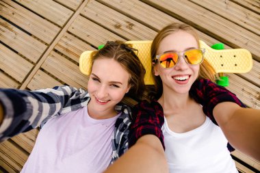 Hipster kıyafeti ile yalan ahşap iskele üzerinde selfie yapma iki genç kız