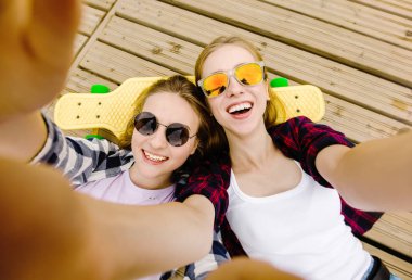 Hipster kıyafeti ile yalan ahşap iskele üzerinde selfie yapma iki genç kız