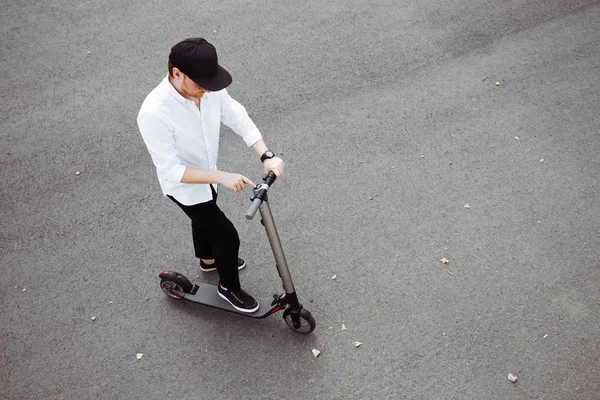 Homem moderno vestido camisa branca e calças pretas de pé na rua com scooter elétrico — Fotografia de Stock