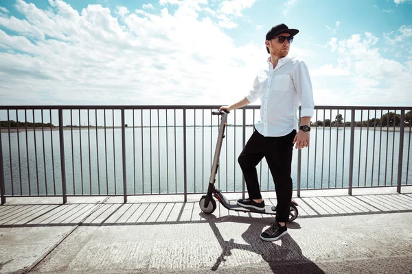 Moderne mens gekleed wit overhemd en een zwarte broek permanent op de straat met elektrische scooter — Stockfoto