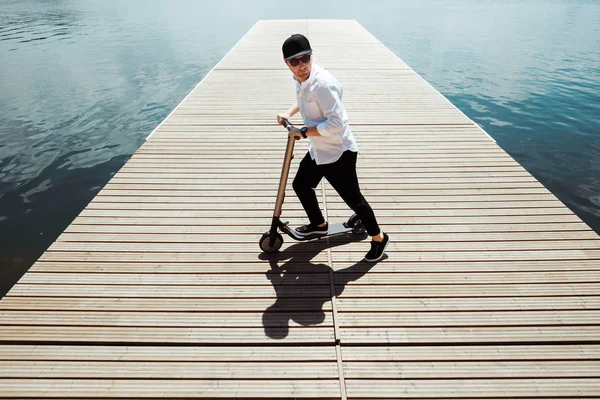 Foto van de moderne mens met elektrische scooter op een houten pier — Stockfoto