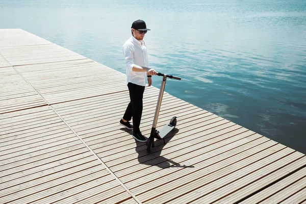 Fotografii współczesnego człowieka z skuter elektryczny o drewnianym molo — Zdjęcie stockowe
