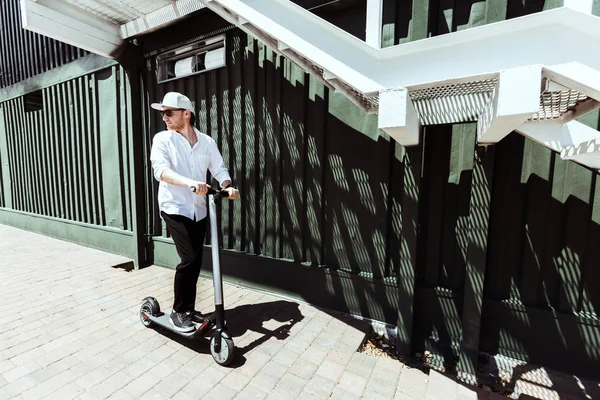 Homem moderno vestido camisa branca e calças pretas de pé na rua com scooter elétrico — Fotografia de Stock