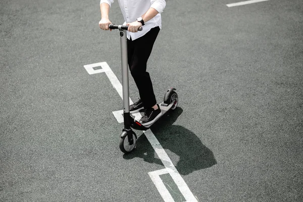Nogi mężczyzny w stylowy strój stanąć na skuter elektryczny na ulicy — Zdjęcie stockowe