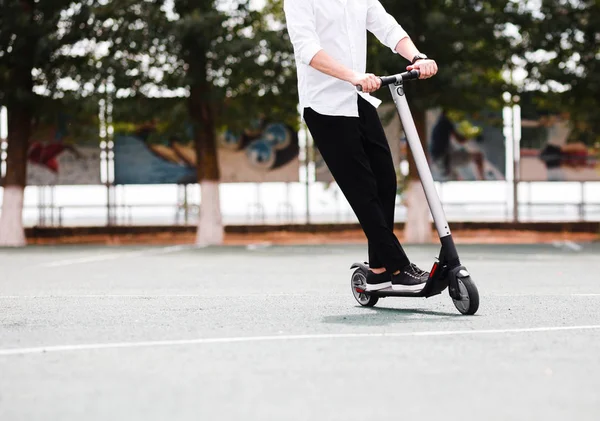 Moderne mens in stijlvolle zwart-witte outfit paardrijden elektrische scooter in de stad — Stockfoto