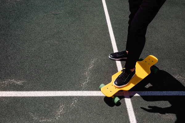 Close up foto do homem moderno em desgaste elegante mantendo os pés no skate amarelo — Fotografia de Stock