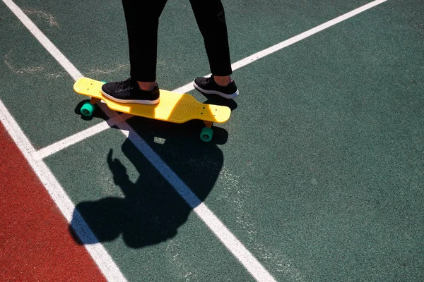 Close up foto do homem moderno em desgaste elegante mantendo os pés no skate amarelo — Fotografia de Stock