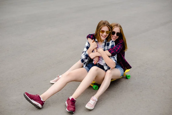 Twee vriendinnen plezier glimlachend gele longboard rijden op de straat. Vriendschap concept — Stockfoto