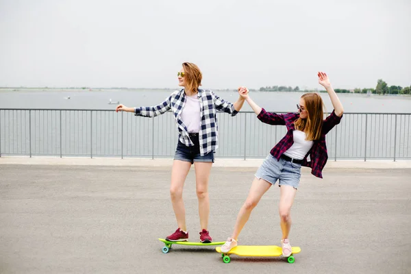 Dwa uśmiechający się koleżanki, Nauka jazdy longboard z pomagając sobie wzajemnie. Pojęcie przyjaźni — Zdjęcie stockowe