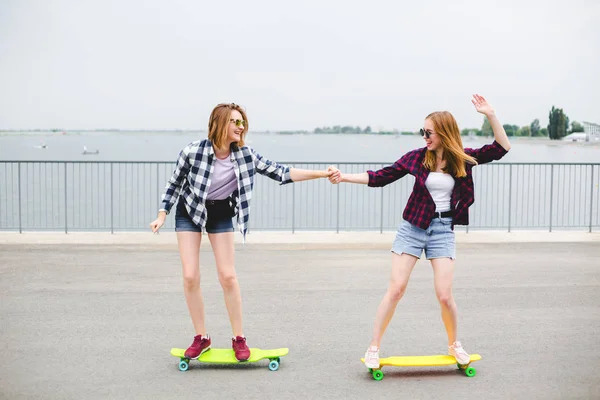 Duas amigas sorridentes aprendendo a andar de longboard ajudando umas às outras. Conceito de amizade — Fotografia de Stock