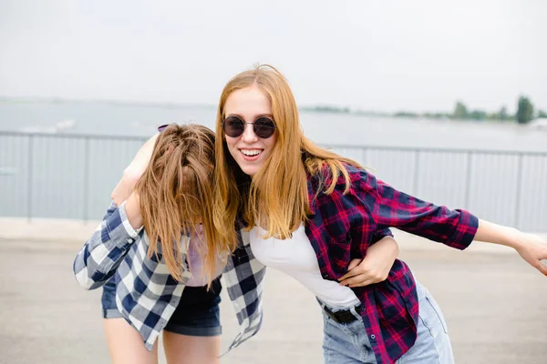 Dos amigas sonrientes abrazándose en la calle. Vacaciones, vacaciones, amor y concepto de amistad —  Fotos de Stock