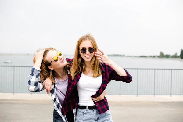 Twee vriendinnen knuffelen elkaar op straat glimlachen. Vakantie, vakantie, liefde en vriendschap concept — Stockfoto