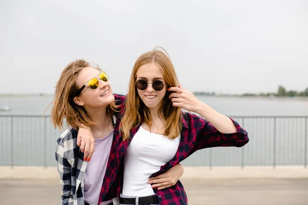 Twee vriendinnen knuffelen elkaar op straat glimlachen. Vakantie, vakantie, liefde en vriendschap concept — Stockfoto