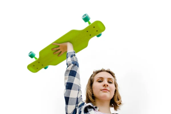 Retrato de uma jovem garota em uma camisa xadrez que segura um longboard em uma mão — Fotografia de Stock