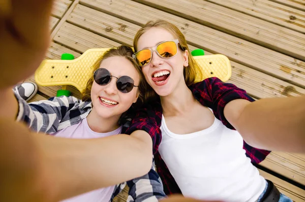 Due giovani ragazza in abito hipster fare selfie mentre sdraiato con sul molo di legno — Foto Stock