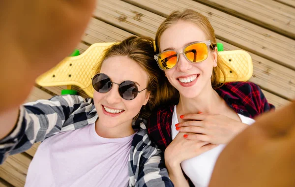 Δύο νεαρό κορίτσι σε στολή hipster κάνοντας selfie ενώ ξαπλωμένη με την ξύλινη προβλήτα — Φωτογραφία Αρχείου